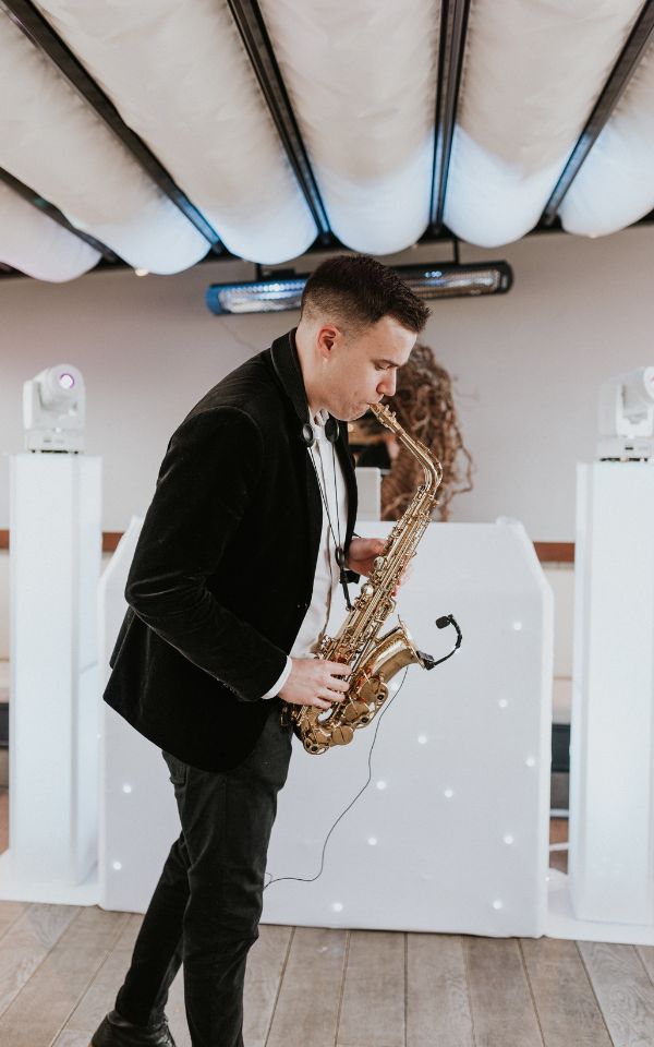 Saxophone player and DJ playing at wedding with traditional attire and dancing<br />

